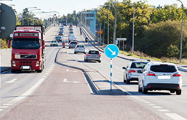 Bilar och lastbilar kör öveer en trefilig bro, Nockebybron.